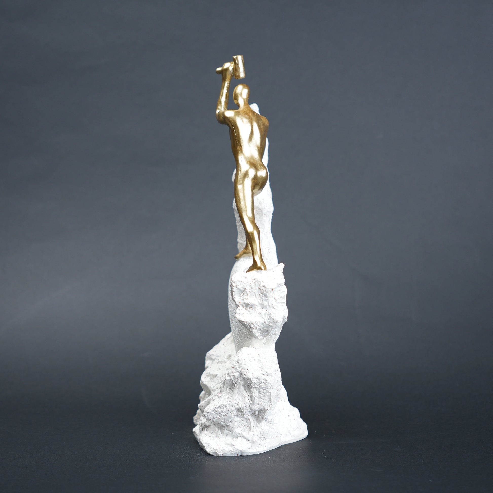 Teamwork climber figurine with gold figures pushing metallic sphere on textured rock base in black and white variants