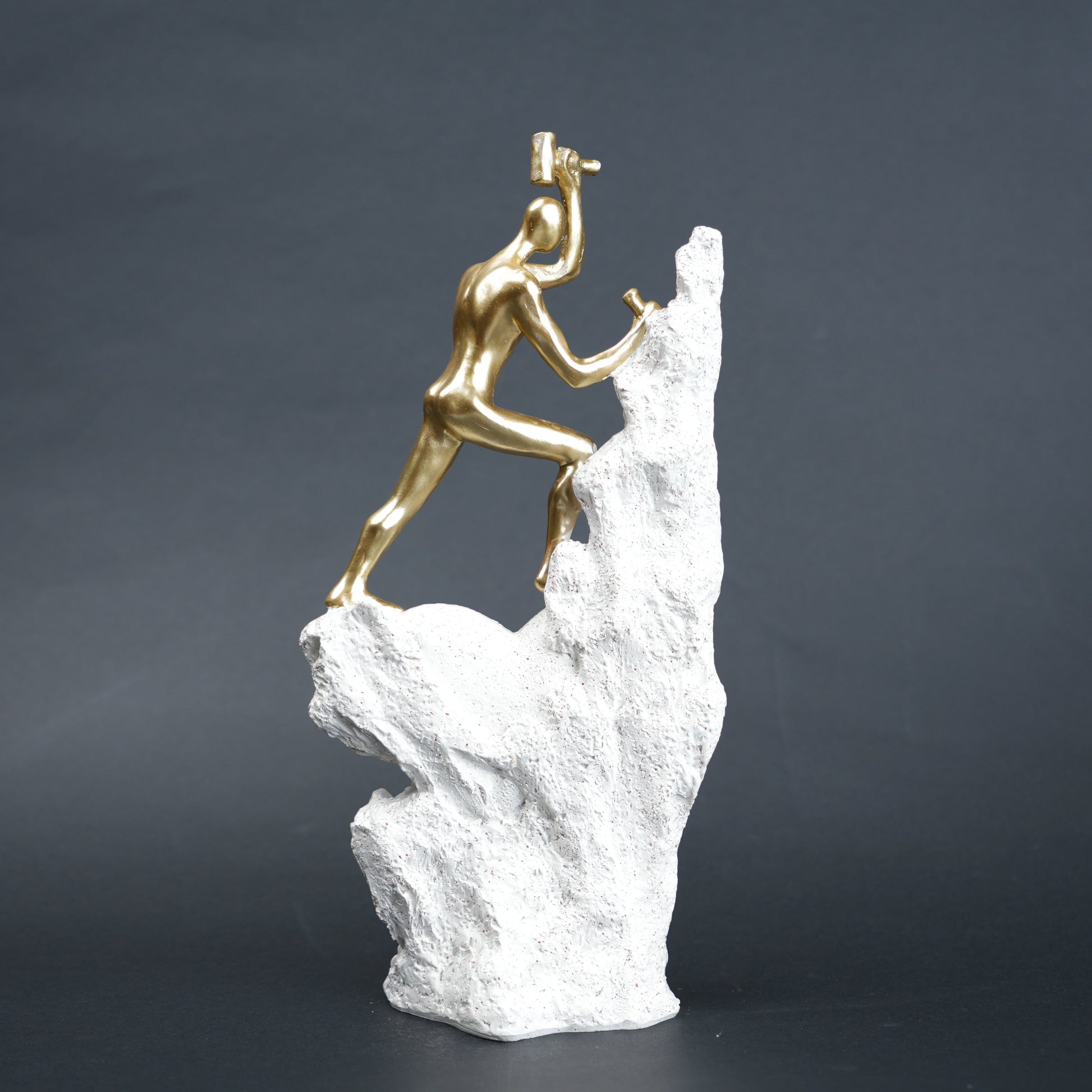 Teamwork climber figurine with gold figures pushing metallic sphere on textured rock base in black and white variants