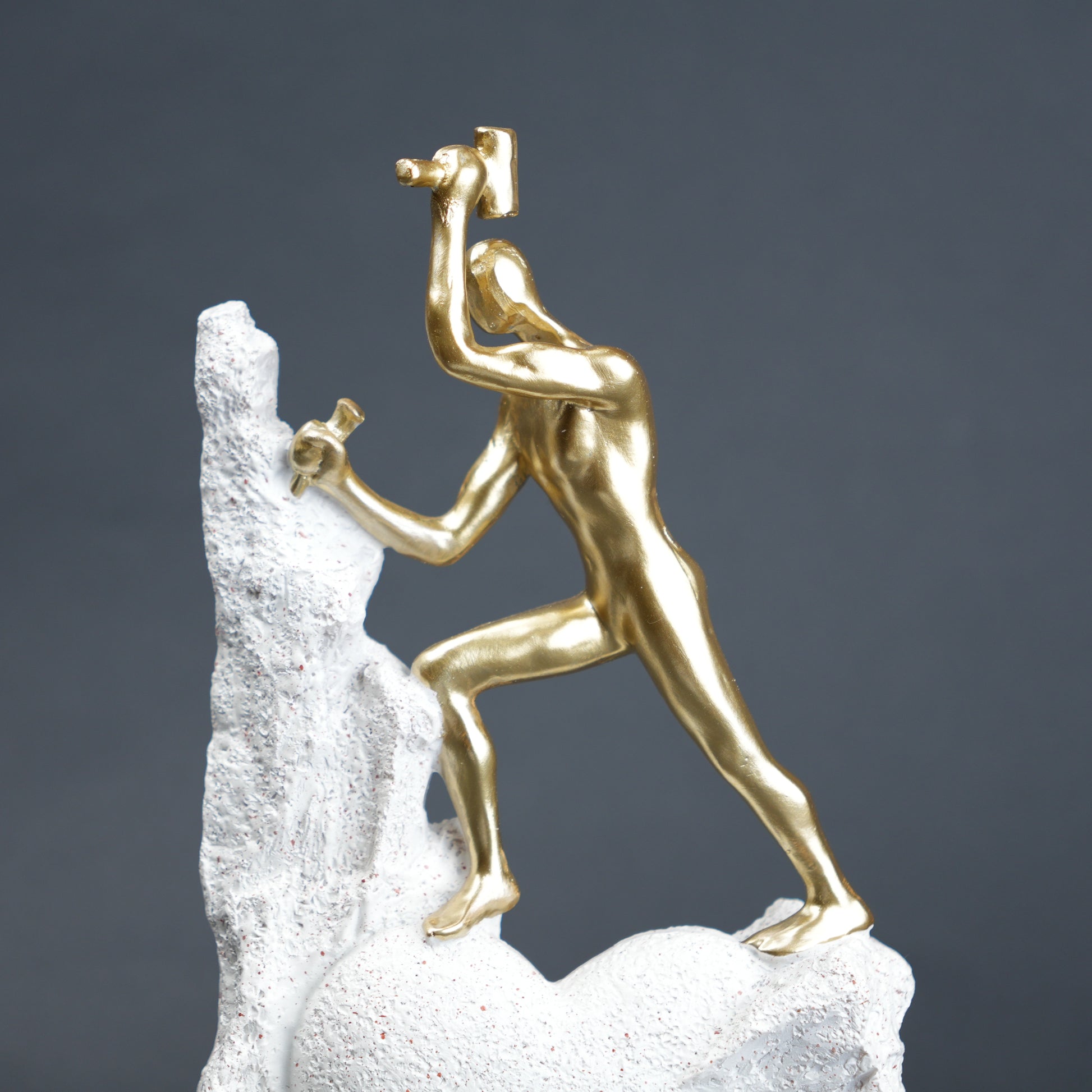 Teamwork climber figurine with gold figures pushing metallic sphere on textured rock base in black and white variants