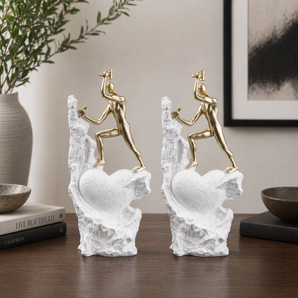 Teamwork climber figurine with gold figures pushing metallic sphere on textured rock base in black and white variants