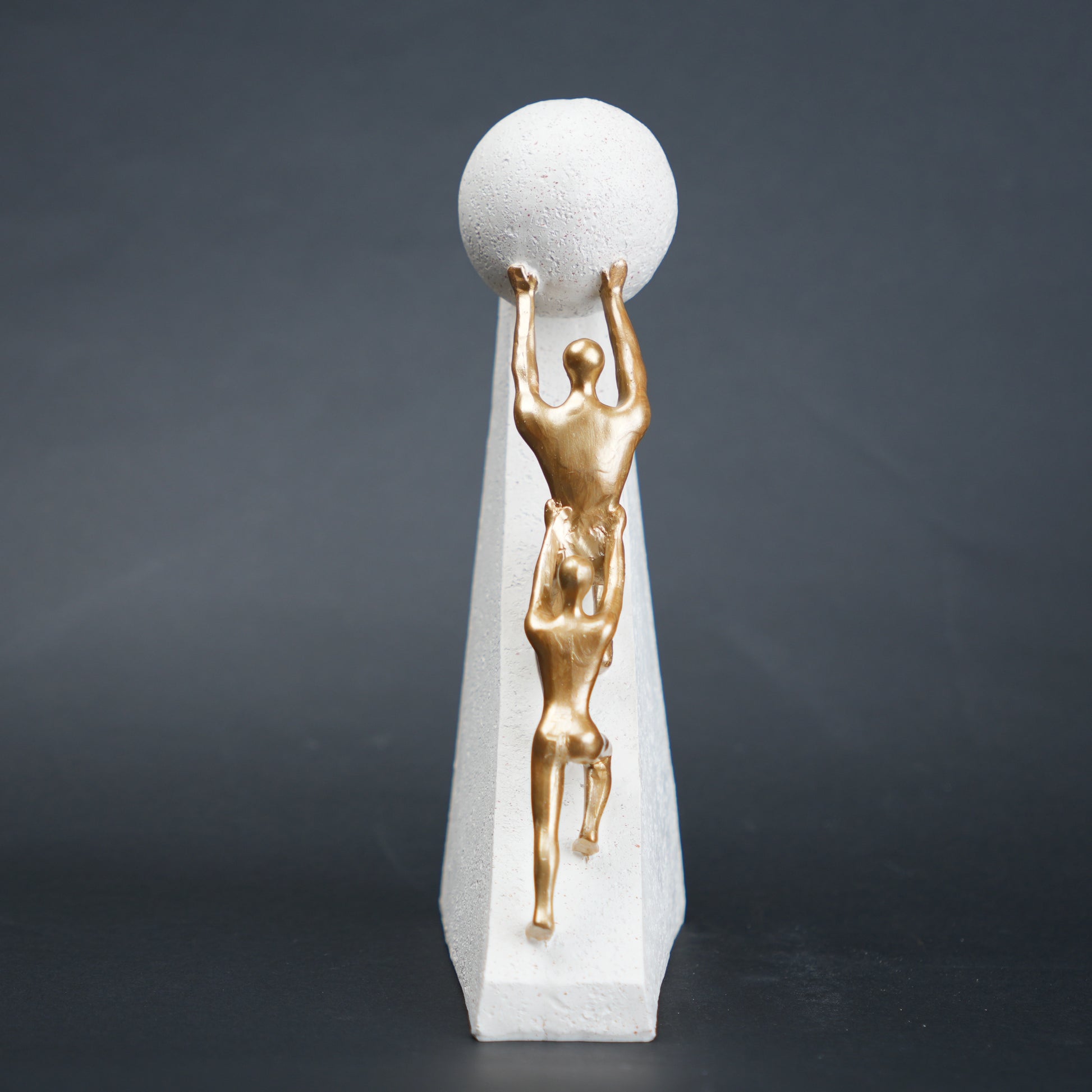 Mountain climber leadership sculpture with gold figurines guiding metallic sphere on textured stone base in black and white variants