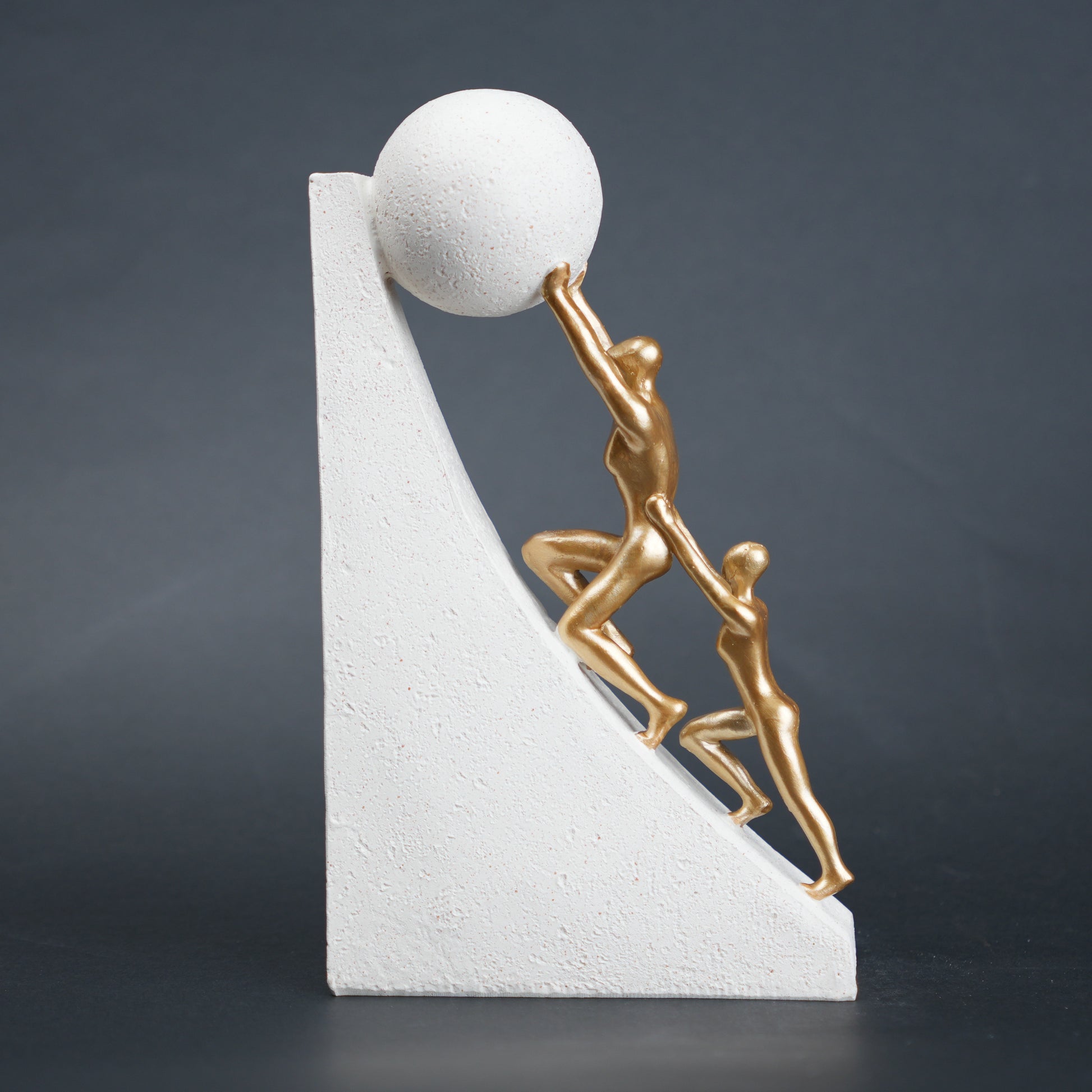 Mountain climber leadership sculpture with gold figurines guiding metallic sphere on textured stone base in black and white variants