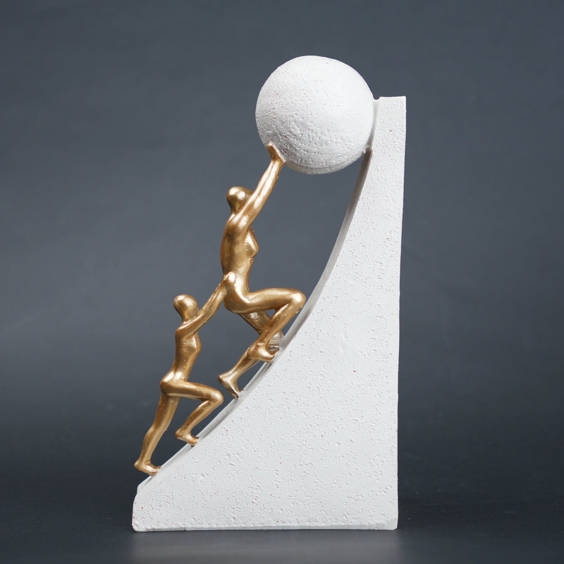 Mountain climber leadership sculpture with gold figurines guiding metallic sphere on textured stone base in black and white variants