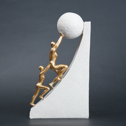 Mountain climber leadership sculpture with gold figurines guiding metallic sphere on textured stone base in black and white variants