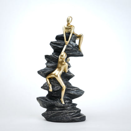 Mountain climber figurine with gold finish ascending layered stone base in black and white variants