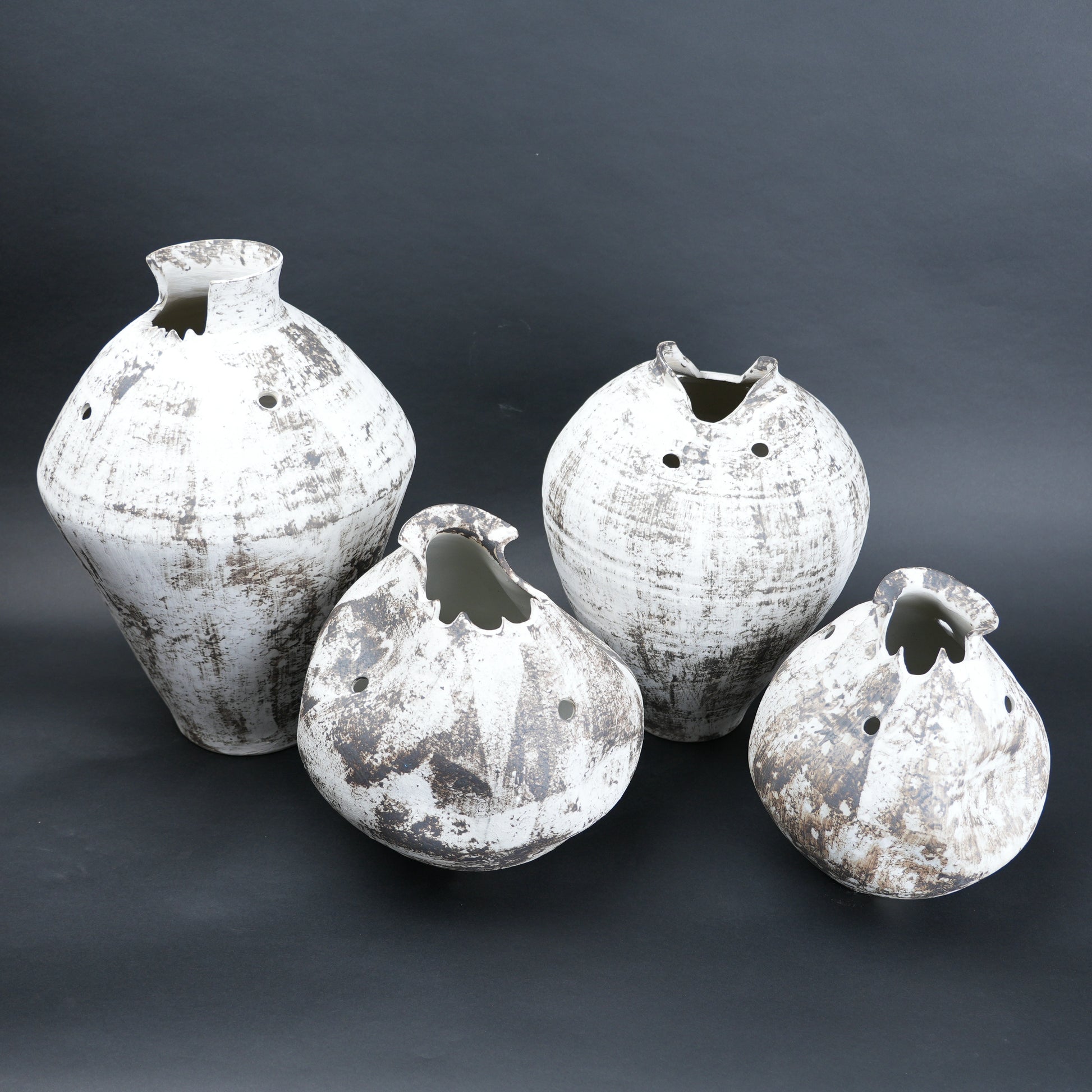 Four textured vases on a white surface