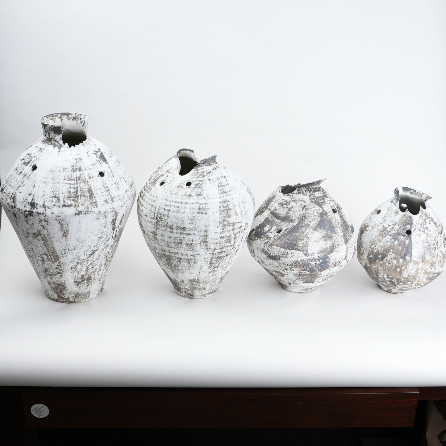 Four textured vases on a white surface