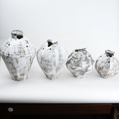 Four textured vases on a white surface