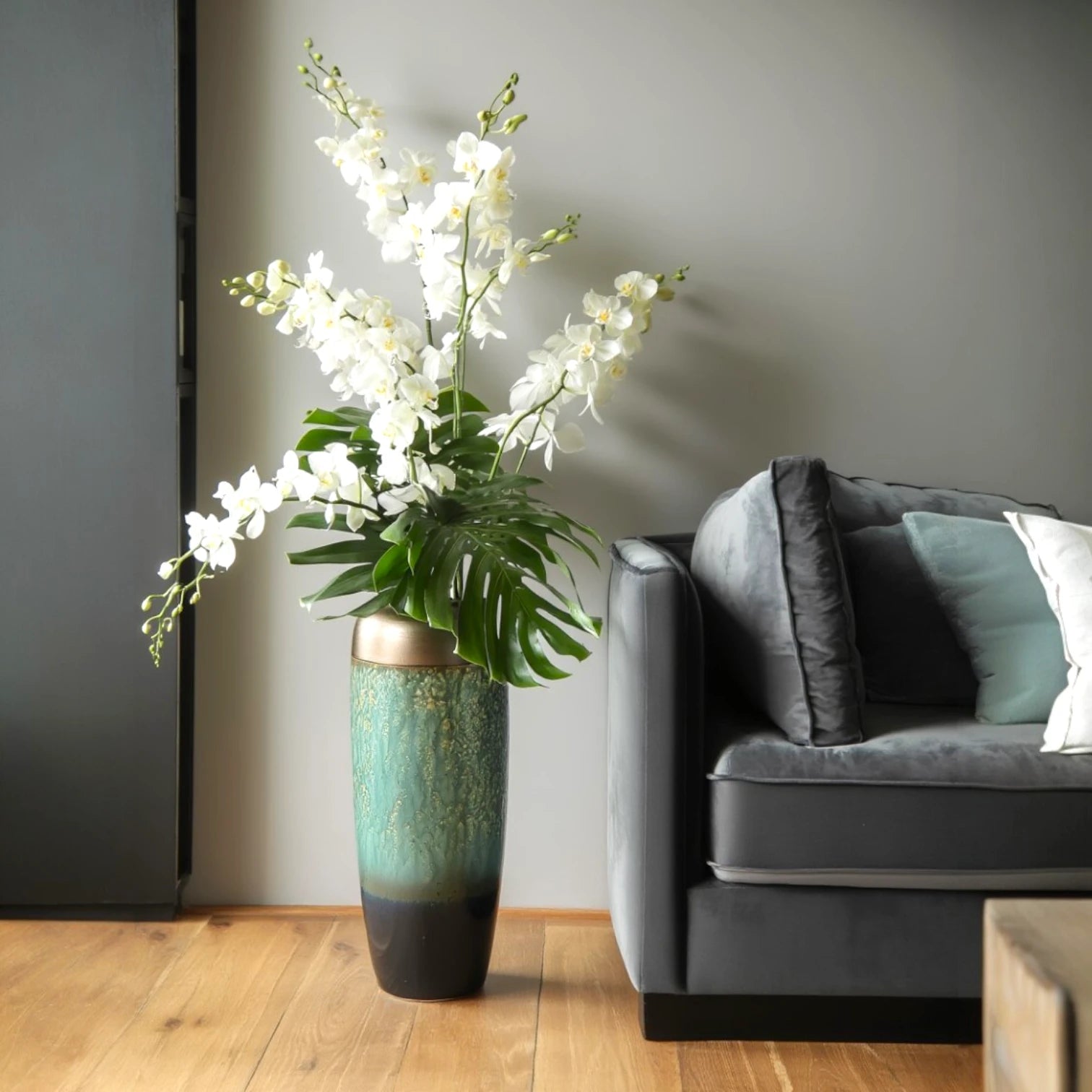 Teal gold vase w/ orchids by velvet sofa