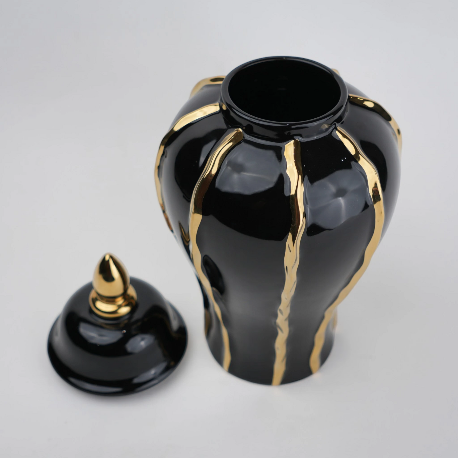 Black ceramic decorative jar with gold flowing accents and lid