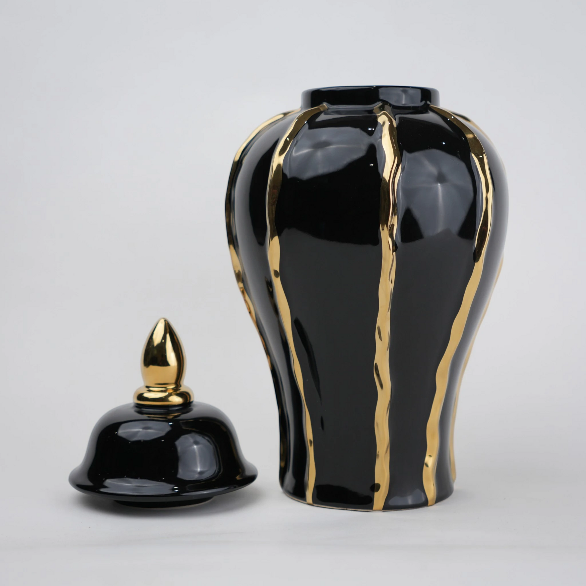 Black ceramic decorative jar with gold flowing accents and lid