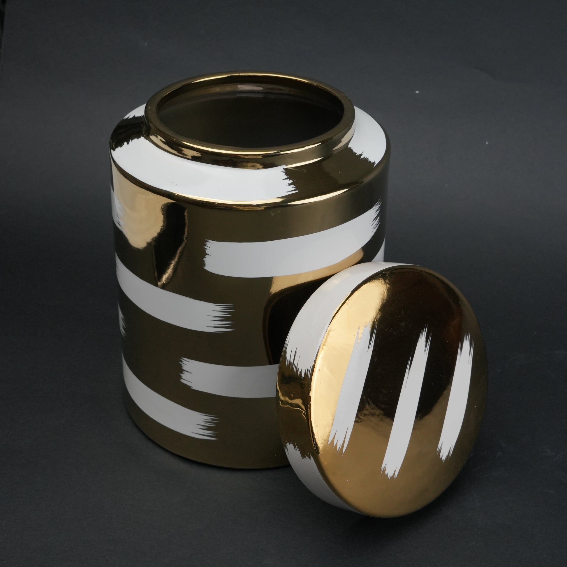 Gold decorative metal jar with white brushstroke design and matching lid