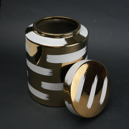 Gold decorative metal jar with white brushstroke design and matching lid