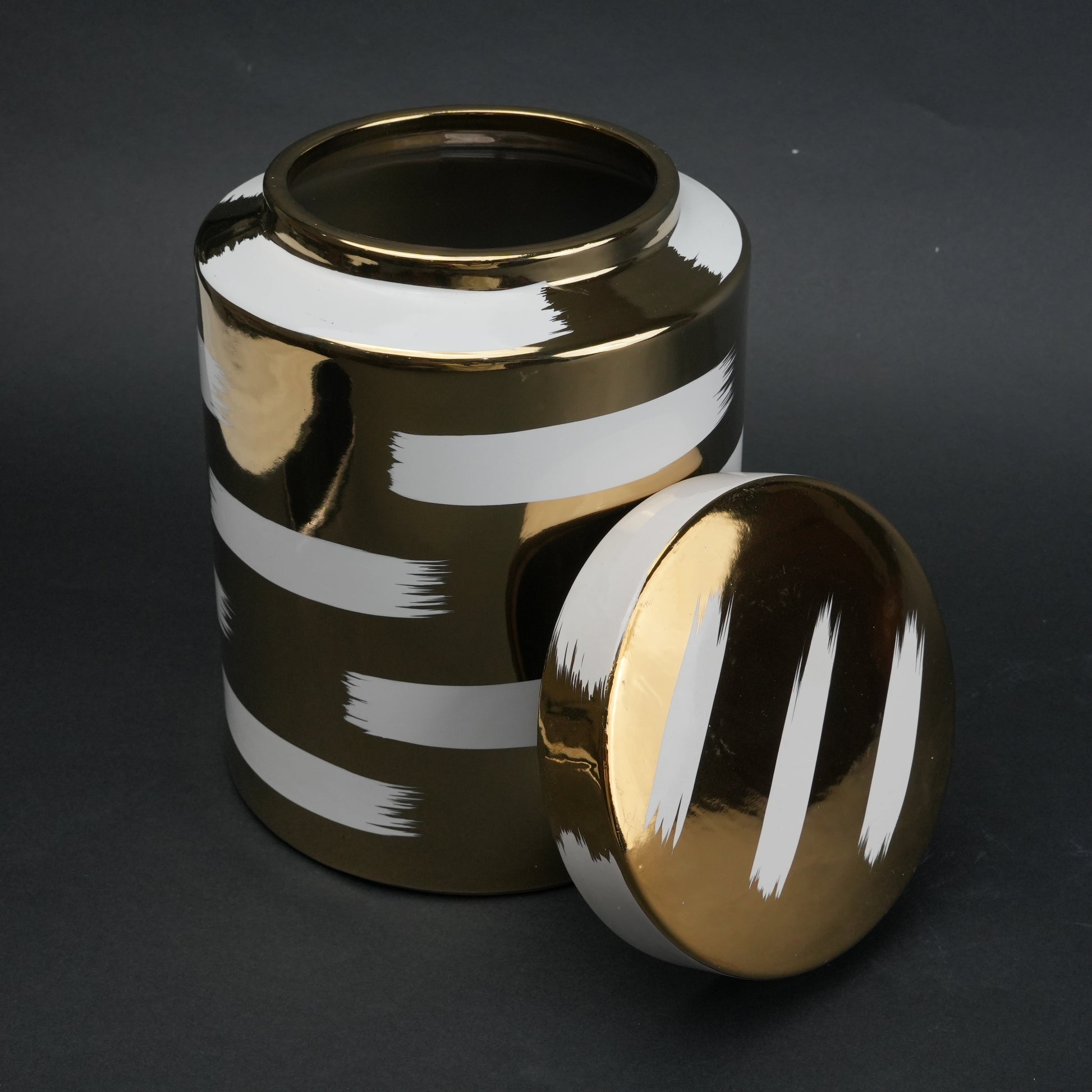 Gold decorative metal jar with white brushstroke design and matching lid