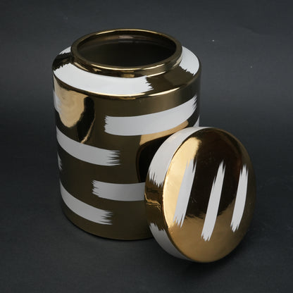 Gold decorative metal jar with white brushstroke design and matching lid
