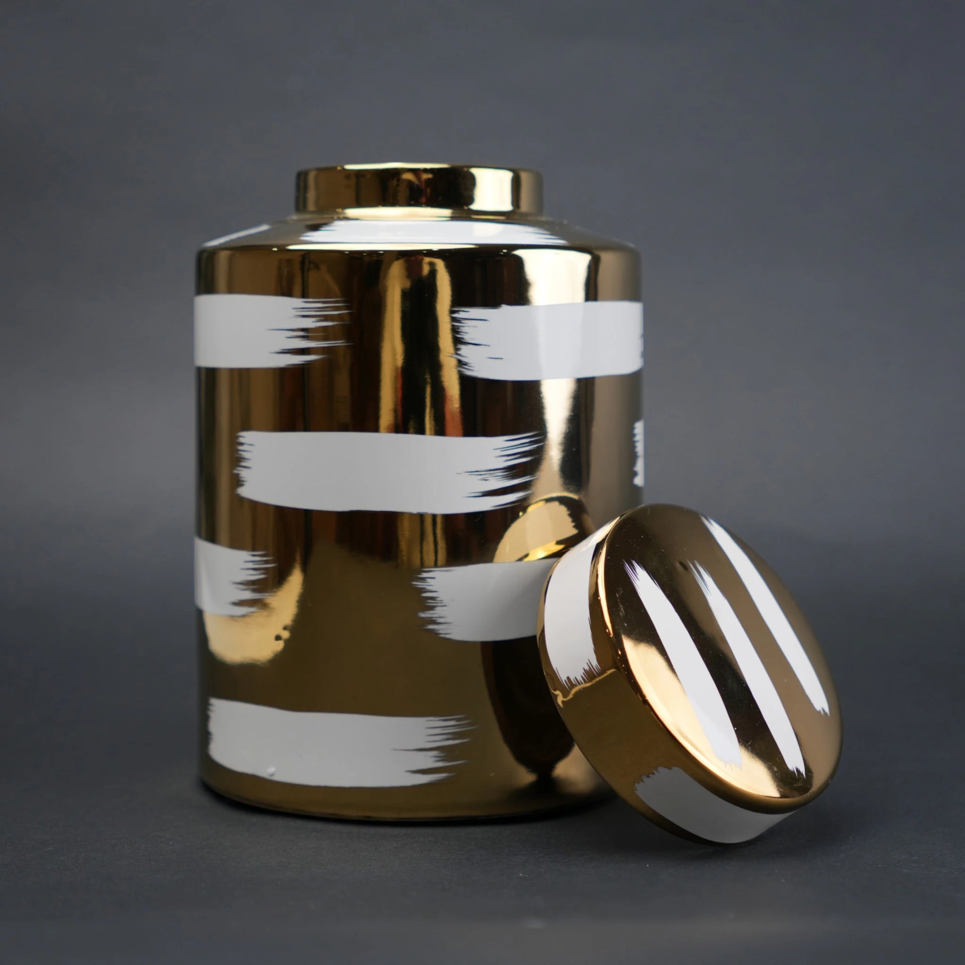 Gold decorative metal jar with white brushstroke design and matching lid