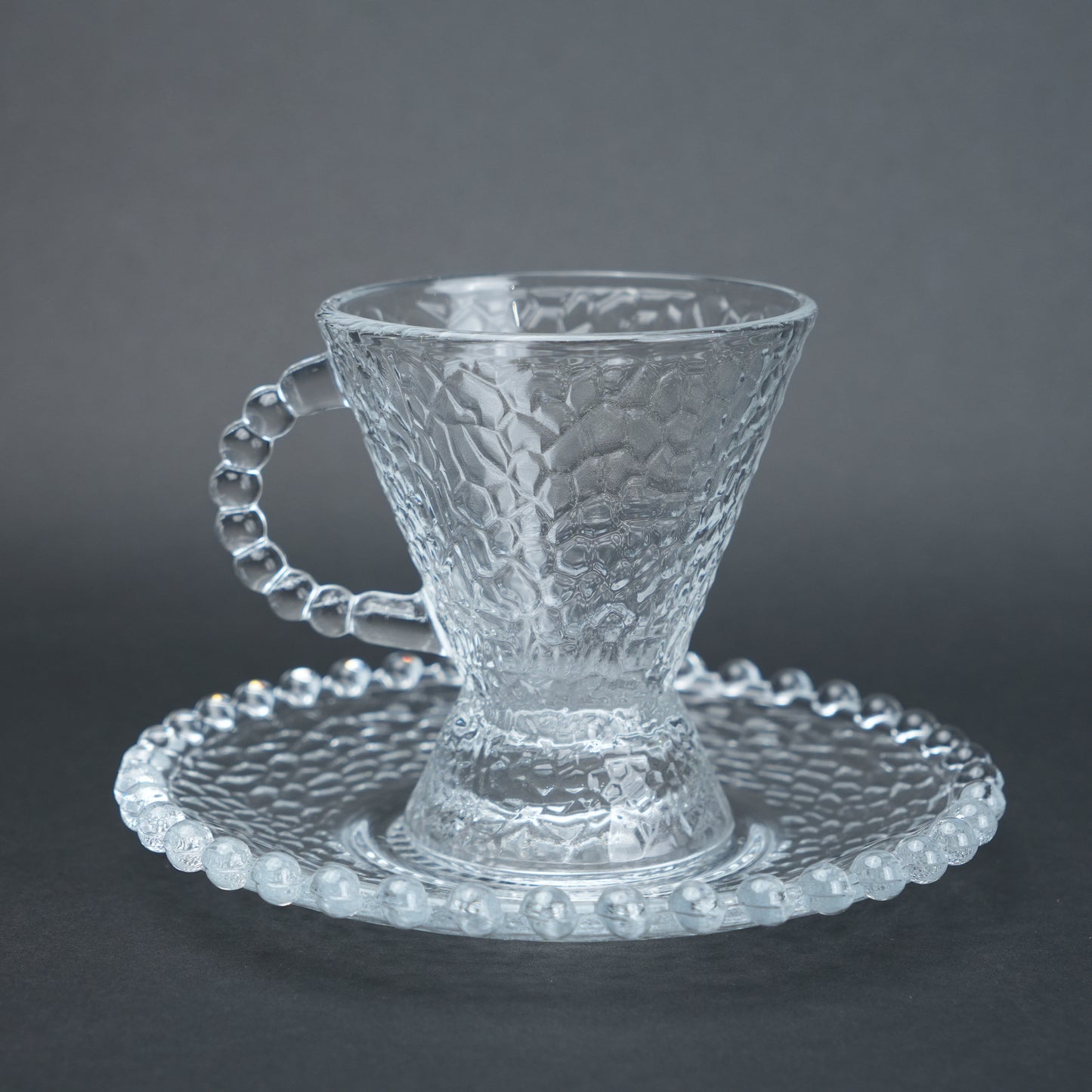 clear textured glass flared tea cup and saucer set with beaded handle for modern table setting