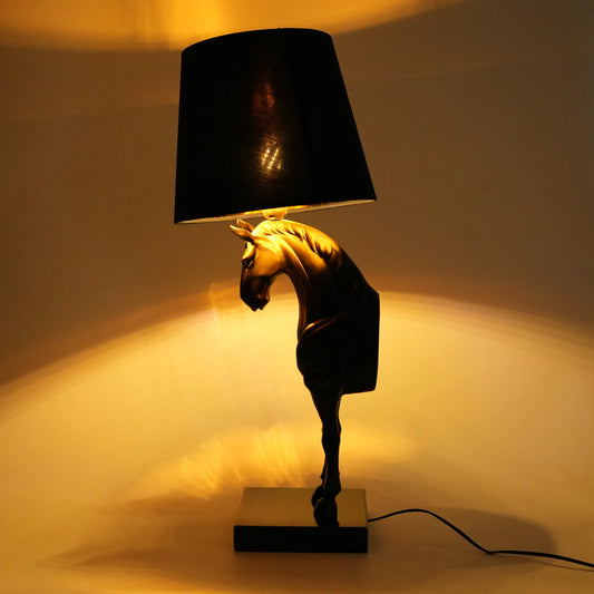 Decorative table lamp with a horse design and black shade on a neutral background