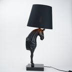 Horse-shaped table lamp with a black shade on a white background