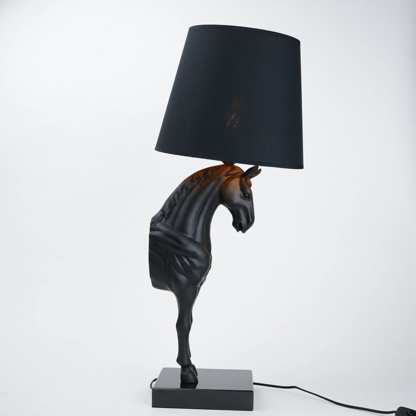 Horse-shaped table lamp with a black shade on a white background