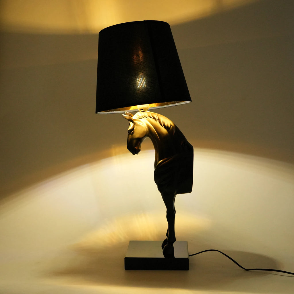 Decorative table lamp with horse head design and black shade on a neutral background