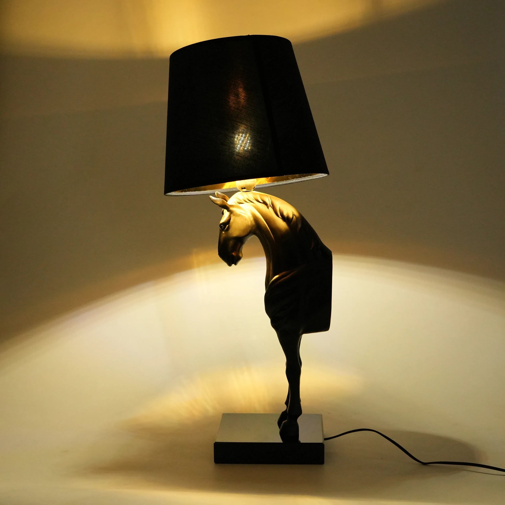 Decorative table lamp with horse head design and black shade on a neutral background