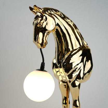 Golden horse table lamp with a sculpted horse base holding a frosted spherical globe light, featuring a smooth metallic finish and a structured base designed for soft ambient lighting and decorative use.