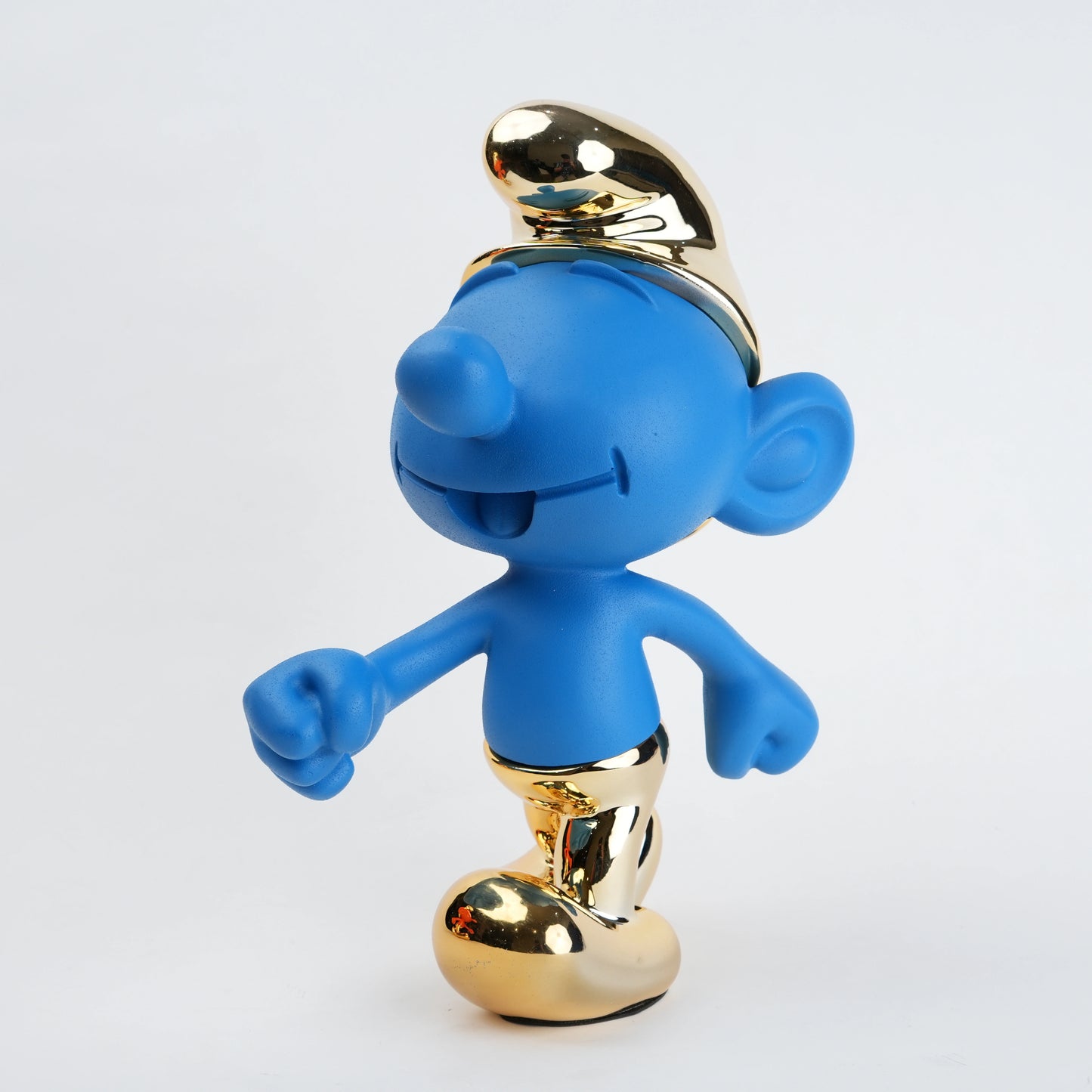 Blue Smurf figurine with gold top hat and shoes on a white background
