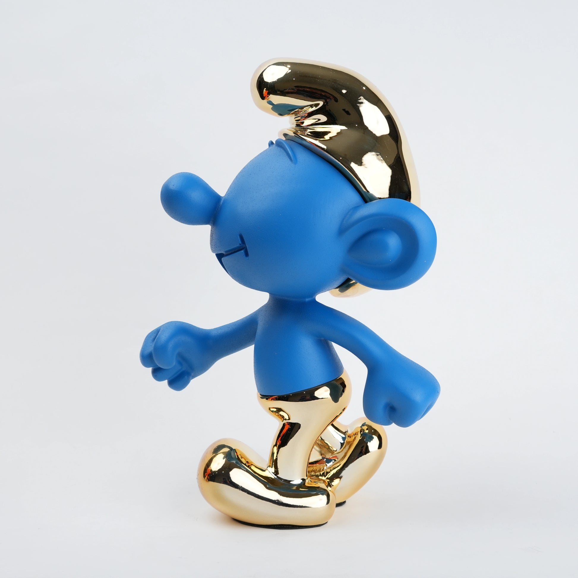 Blue Smurf figurine with gold crown and shoes on a white background