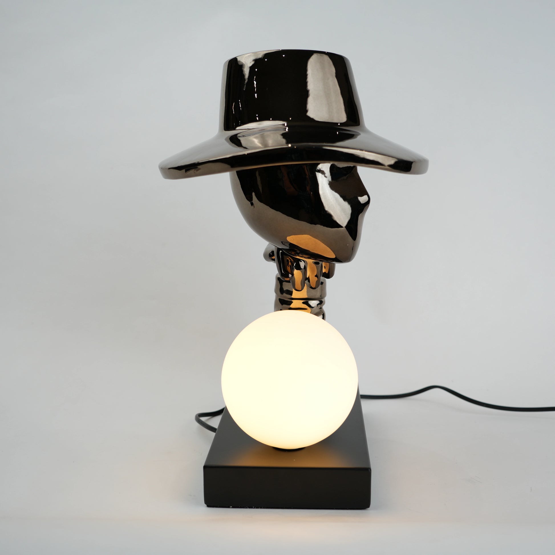 Black lamp with a round shade and white bulb on a gray background