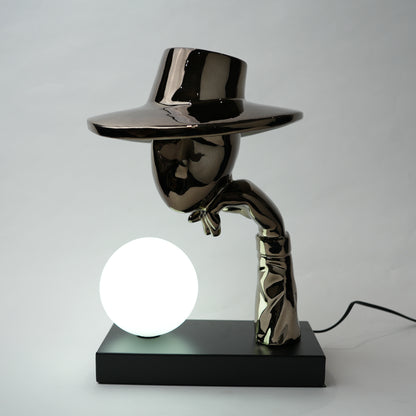 Decorative lamp with a metallic figure and a round light bulb on a plain background