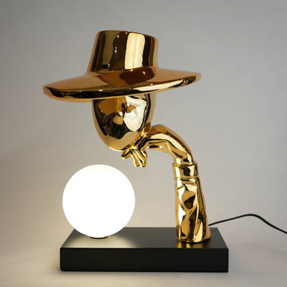 Gold lamp with a unique design on a black base against a gray background