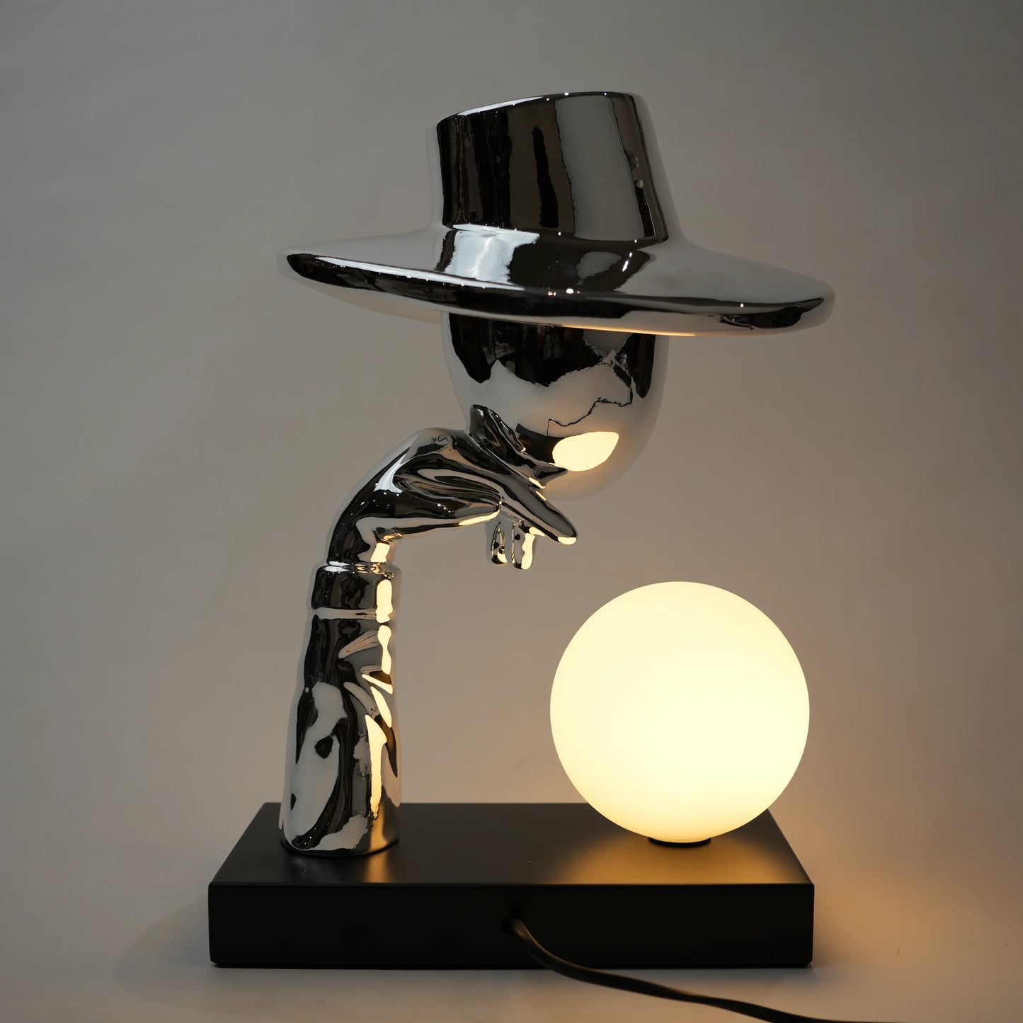 Modern table lamp with a hand holding a light bulb design on a dark background
