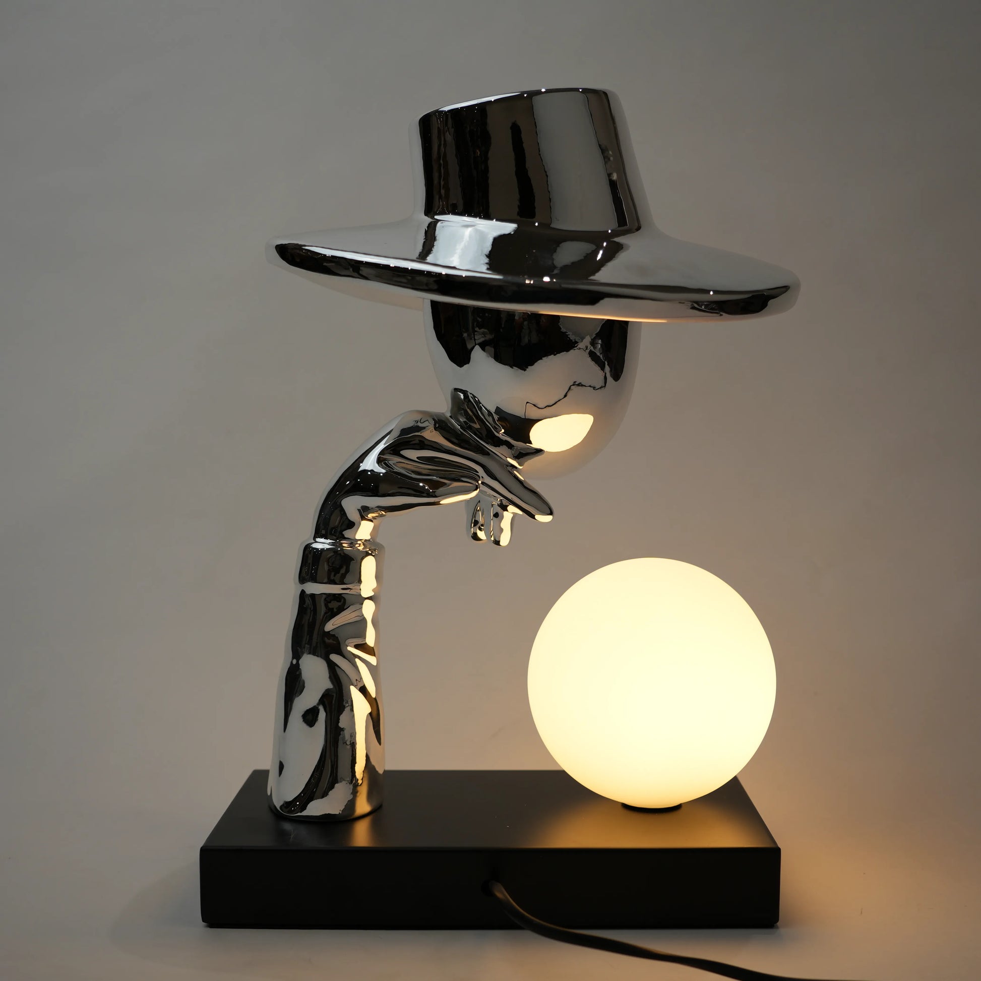 Modern table lamp with a hand holding a light bulb design on a dark background