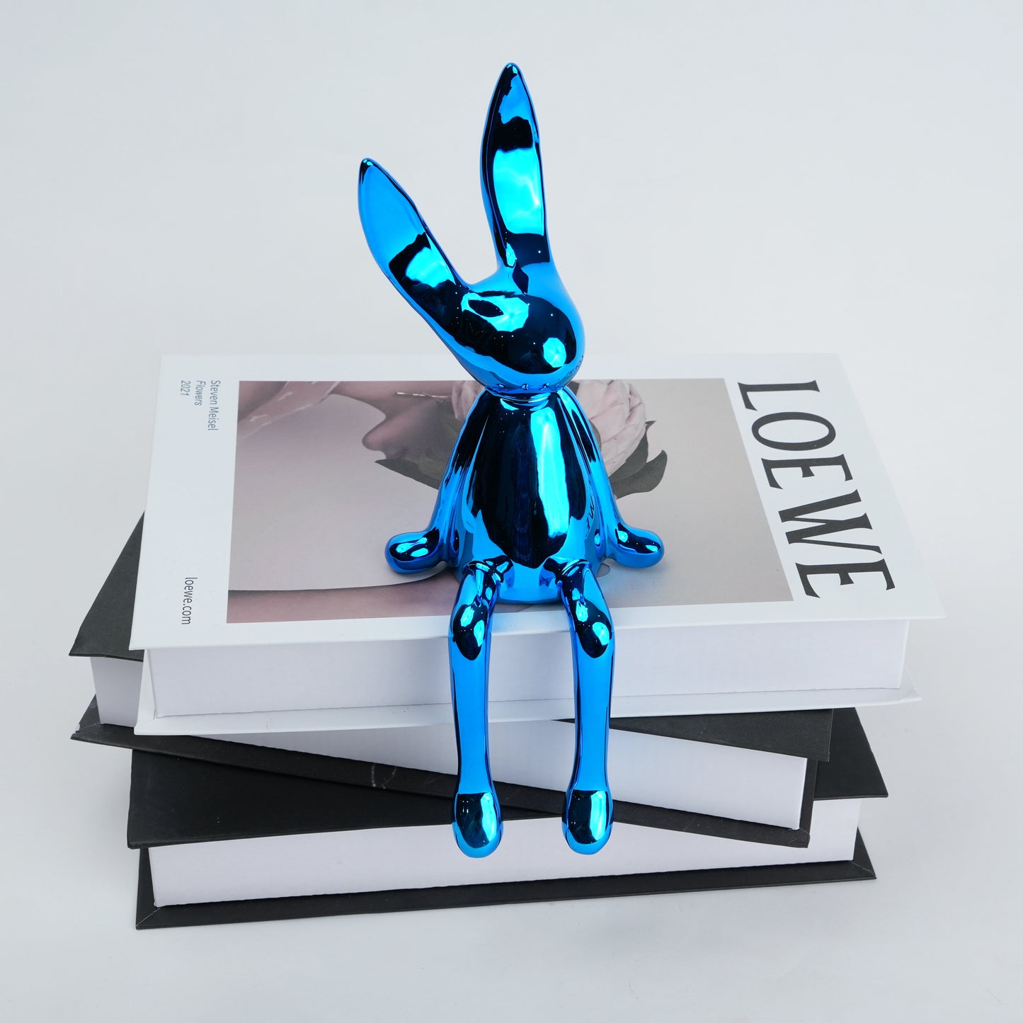 Resin bunny figurine with elongated ears and a minimal seated design, featuring smooth contours and extended legs for edge placement, available in matte and reflective electroplated finishes.