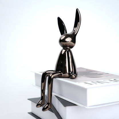 Metallic rabbit sculpture on a white surface with a light gray background