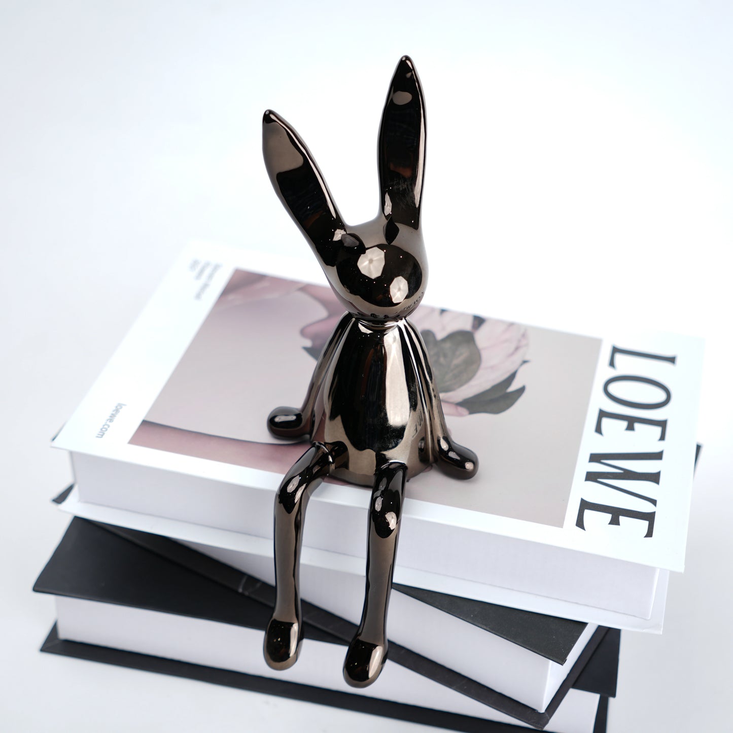 Metallic rabbit-shaped hook on a stack of books with a visible brand name.