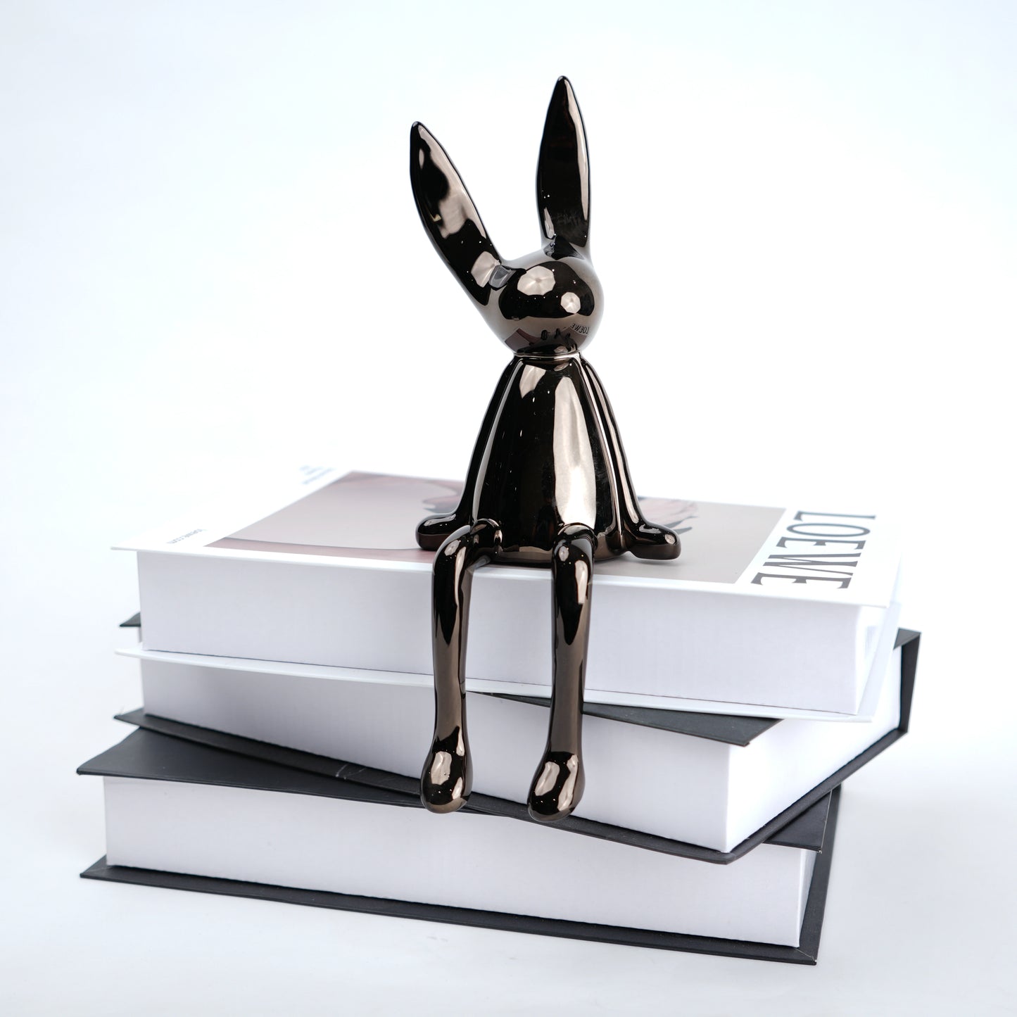 Resin bunny figurine with elongated ears and a minimal seated design, featuring smooth contours and extended legs for edge placement, available in matte and reflective electroplated finishes.