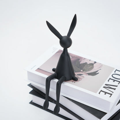 Black rabbit-shaped object on a stack of books with a white background