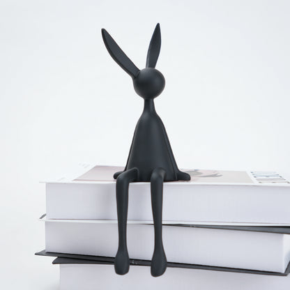 Black rabbit-shaped bookend on a stack of books with a white background
