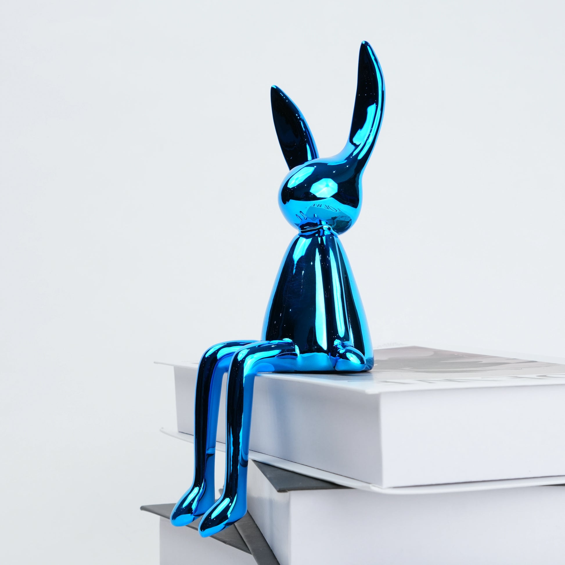 Blue metallic rabbit sculpture on a white surface with a light gray background
