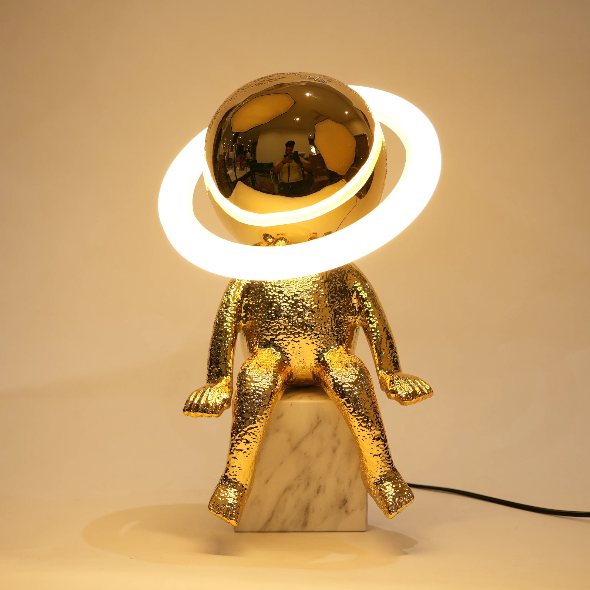Gold astronaut lamp with a round light on a beige background