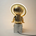 Gold-colored lamp with marble base on a plain background