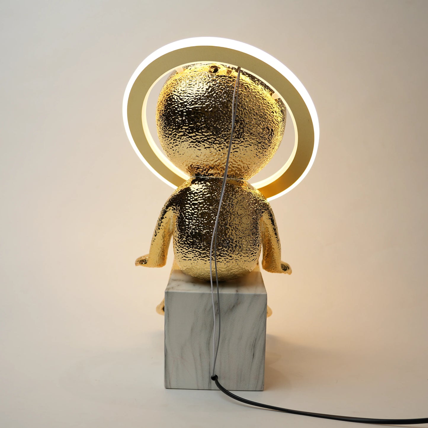 Gold-colored lamp with marble base on a plain background