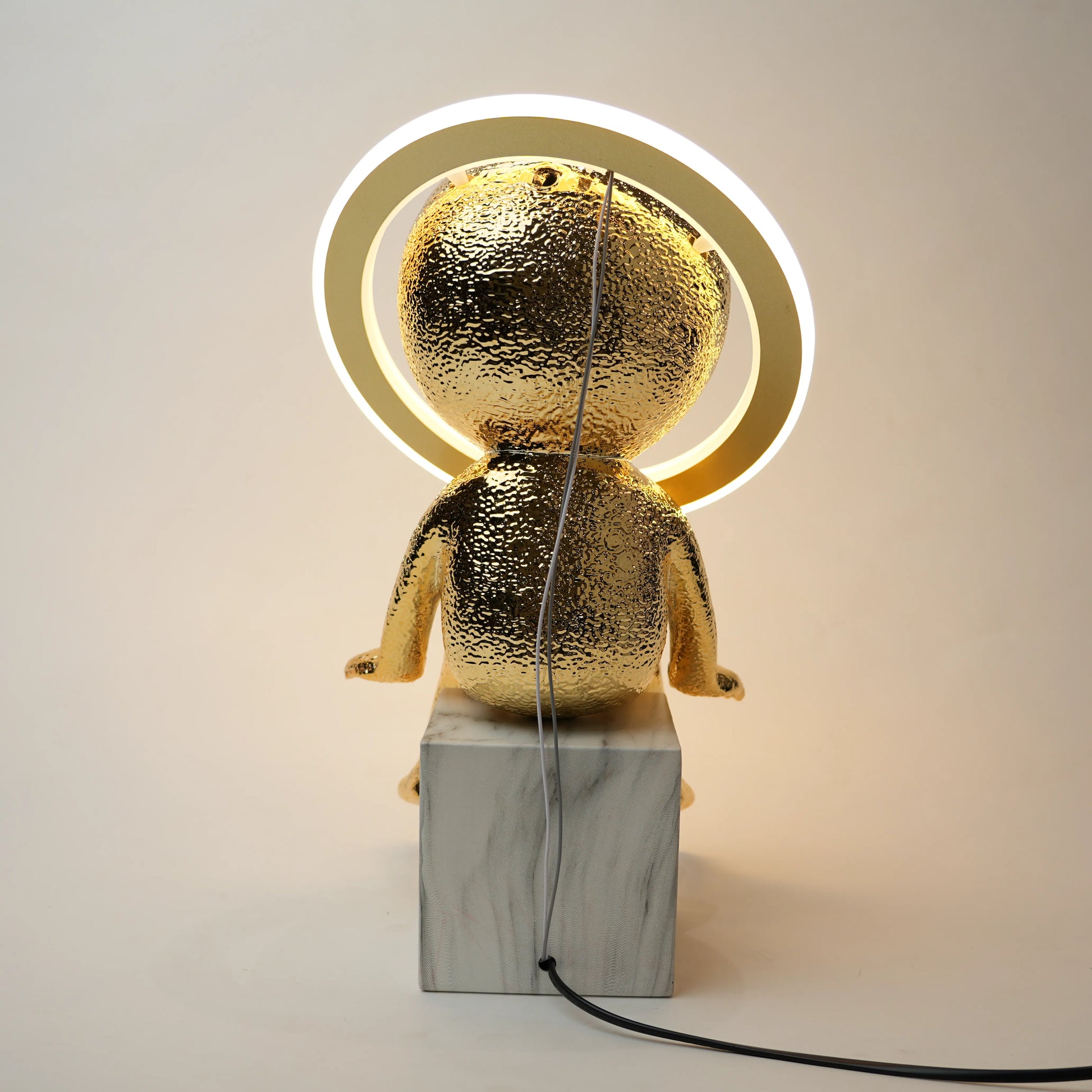 Gold-colored lamp with marble base on a plain background