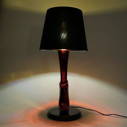 Table lamp with black shade and red base on a neutral background