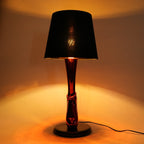 Lamp with a black shade and red base on a neutral background