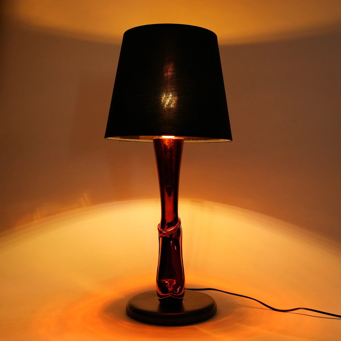 Lamp with a black shade and red base on a neutral background
