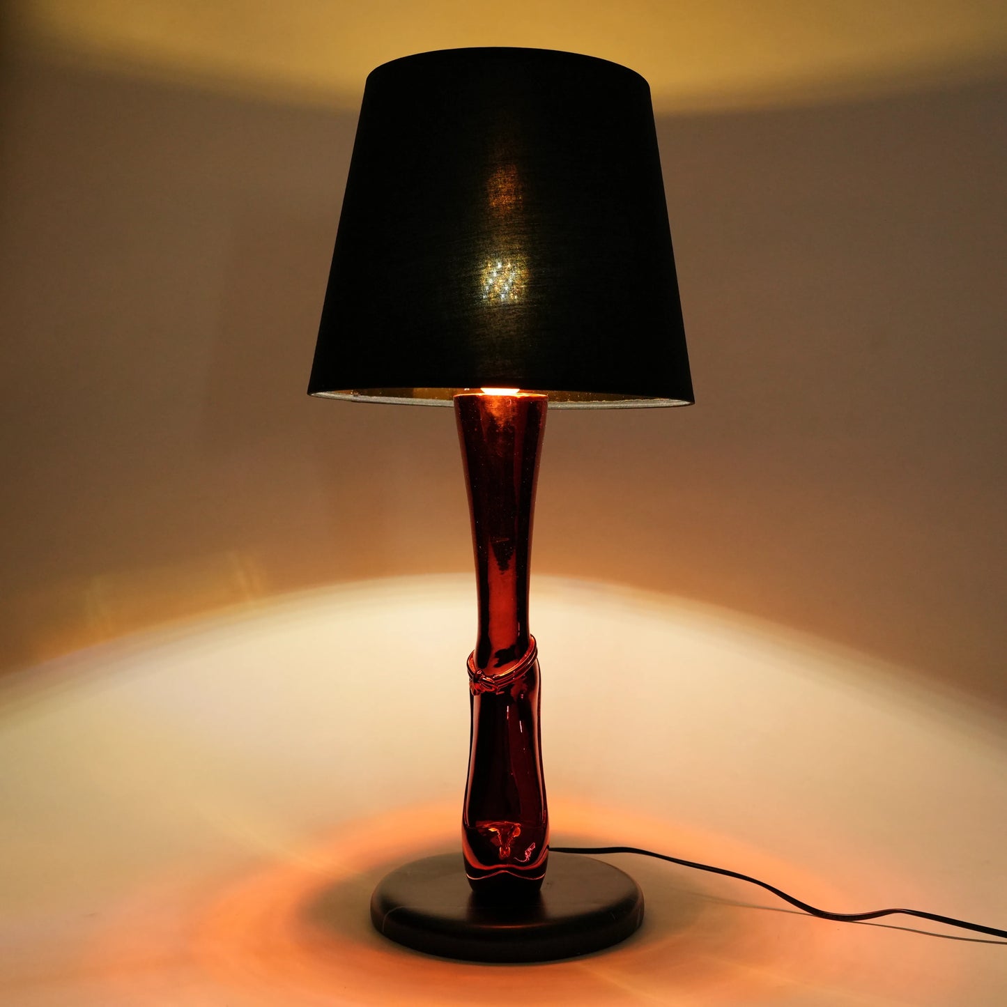 Table lamp with a black shade and red base on a neutral background