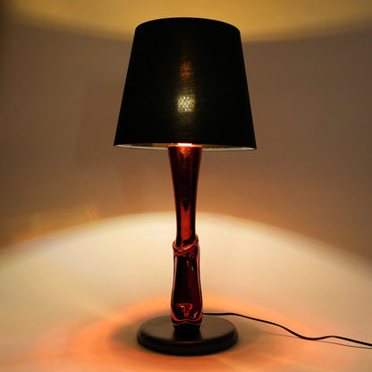 Table lamp with a black shade and red base on a neutral background